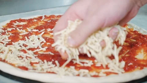 Adding shredded cheese to pizza sauce. Stock Footage 340461316