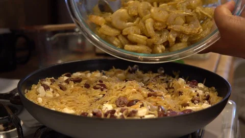 Adding shrimp to gumbo ingredients in frying pan, Closeup Stock Footage 119598970