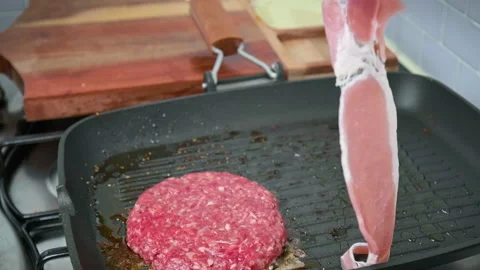 Adding a slice of bacon into a grilling pan in 4K. Stock Footage 153752640