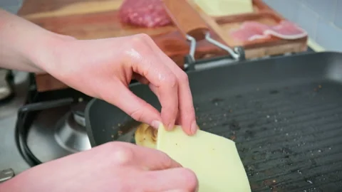 Adding a slice of cheese on top of beefsteak into a grilling pan in 4K. Stock Footage 153743790