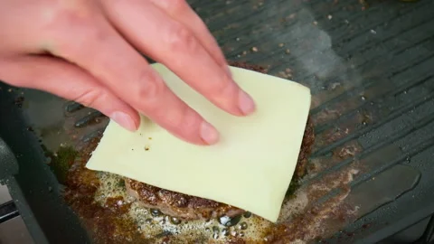Adding a slice of cheese on top of beefsteak into a grilling pan in 4K. Stock Footage 153756676