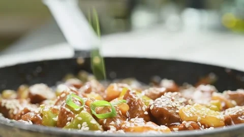 Adding sliced green onion on a sweet and sour pork. Stock Footage 169800518
