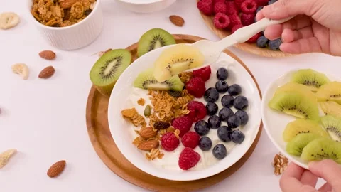 Adding Sliced Kiwi to a Healthy Greek Yogurt Fruit Bowl Stock Footage 337995130