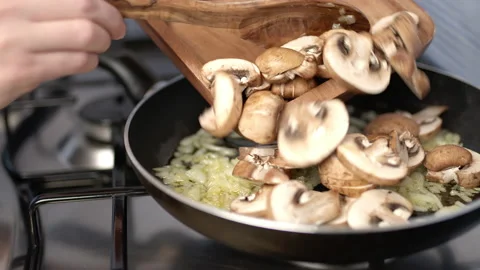 Adding sliced mushroom into risotto in a frying pan. Stock Footage 134690918
