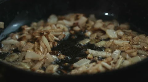 Adding sliced mushrooms to fried onions on the hot pan and stirring it closeup Stock Footage 62477512