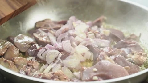 Adding sliced onion to chicken livers in the frying pan. Stock Footage 194920943