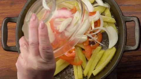 Adding sliced pepper and onion to potatoes frying in a pan Stock-Footage 328310364