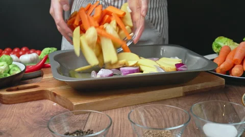 Adding sliced vegetables into an oven pan for roasting in 4k. Stock Footage 145114905
