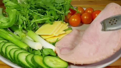 Adding slices of ham to a plate of salad. Stock Footage 221272020