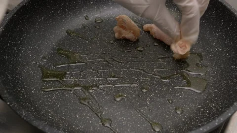 Adding small chicken meat chunks onto a frying pan with hot oil 库存影片 290090249