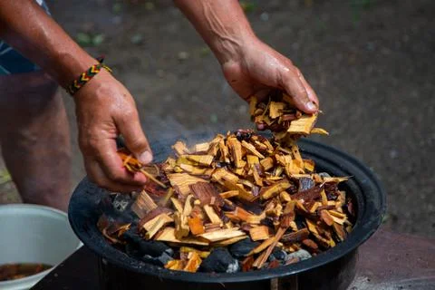 Adding soaked wood chips to the burning charcoal For Smoking Meat On Barbecue. Stock Photos