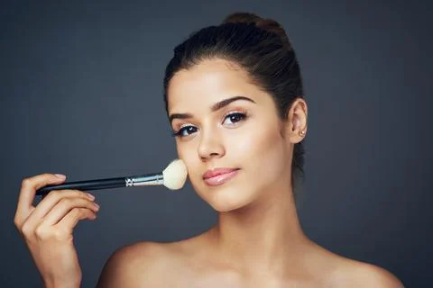 Adding some beauty by adding some blush. Studio shot of a beautiful young woman Stock Photos