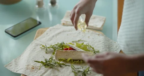 Adding some oil to a dish, brie cheese, green salad, cherry tomatoes, pita,doner Stock Footage 134458984