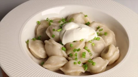 Adding sour cream to hot dumplings sprinkled with fresh green onions Stock Footage 303080452