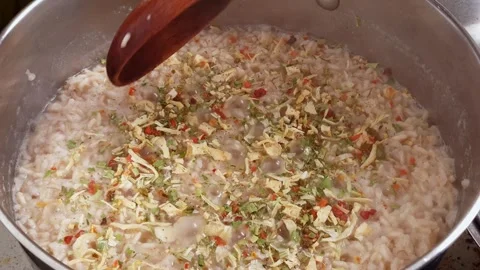 Adding spices and stirring rice in a pot for cooking a delicious meal Stock Footage 341934955