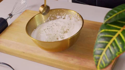Adding spices to beaten egg whites in a golden bowl Vídeo Stock 312720386