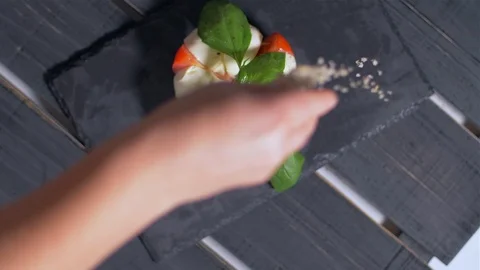 Adding spices to the Caprese salad. Black background Stock Footage 109268972