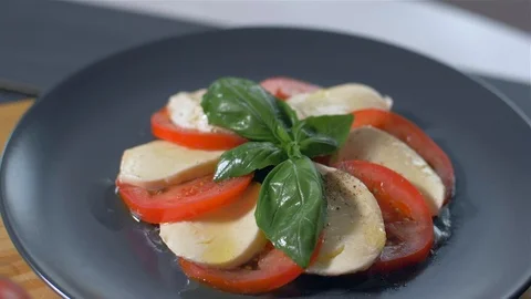 Adding spices to the Caprese salad. Black background Vídeos de archivo 109269739