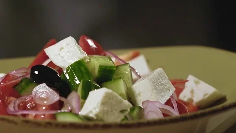 Adding spices to dressed and prepared traditional greek salad in slow motion Stock Footage 76963762
