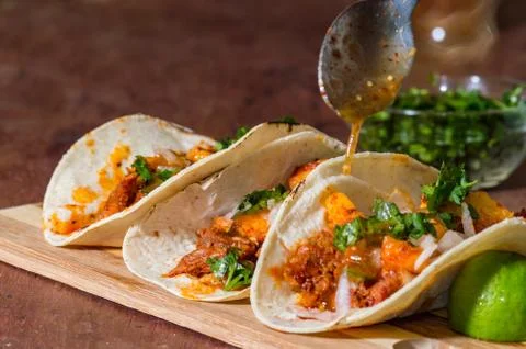 Adding spicy sauce to freshly cooked Mexican tacos Stock Photos
