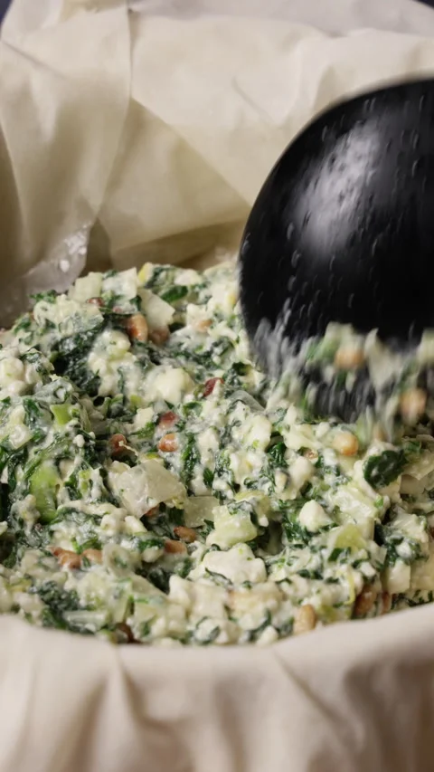 Adding Spinach Feta Pie Filling To Phyllo Dough Pan Close Up Stock Footage 337289751