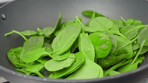Adding spinach into a frying pan in slow-motion in 4k. Stock Footage 146000461