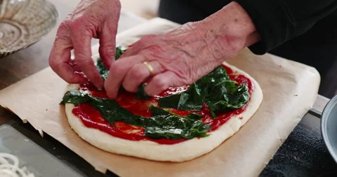 Adding spinach to home made pizza Stock Footage 241606519