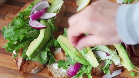 Adding sprouts and black pepper to salmon sandwich Stock Footage 93794109