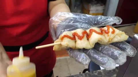 Adding Sriracha Sauce to Korean Fish Cake Skewer close up Stockbeeldmateriaal 337374779
