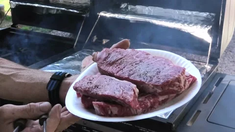 Adding Steak to the Grill Stock Footage 138933354