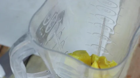 Adding strawberries to mango smoothie Stock Footage 130062764