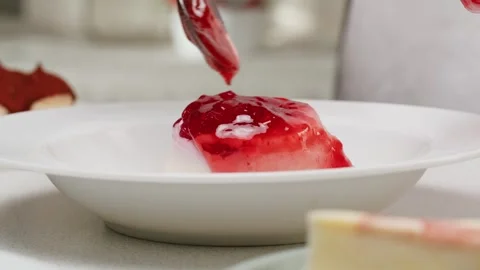 Adding strawberry jam on white panna cotta dessert close-up. Pannacotta Italian Stock Footage 277416981