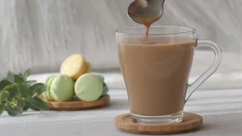 Adding sugar to coffee cup, spoon is stirring sugar in a mug, slow motion Stock Footage 176857492