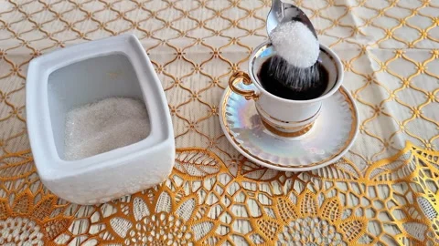 Adding Sugar to a Cup of Coffee on an Elegant Crochet Tablecloth Vidéo 346743561