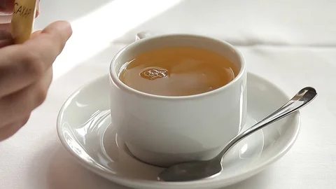 Adding sugar to cup of tea and stirring 库存影片 80489215