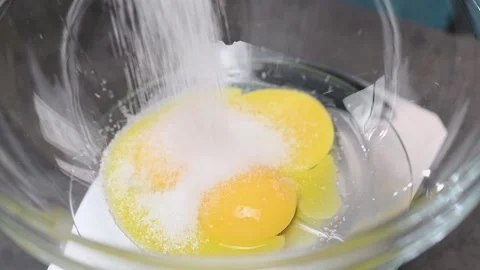 Adding sugar to egg yolks in the glass bowl. Stock Footage 153484785