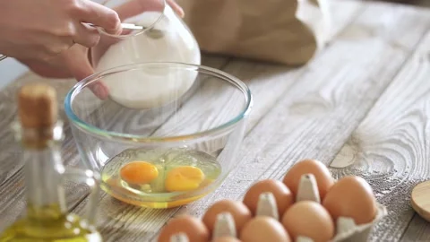 Adding sugar to eggs to make waffle dough. Measuring sugar with a teaspoon t Stock Footage 156209121