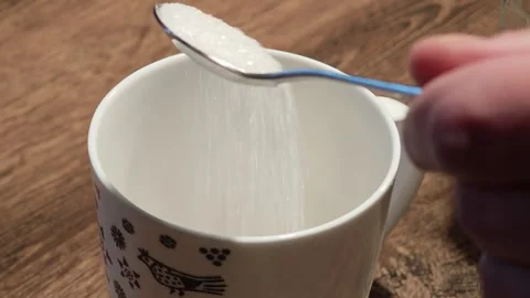 Adding sugar to empty mug on wooden table Vidéo 310407275