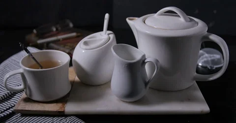 Adding sugar to a nice steaming hot cup of tea from the tea pot Stock Footage 72950925