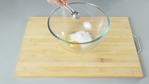Adding sugar to raw eggs in a bowl before beating them. Preparing dough for Stock Footage 232410888