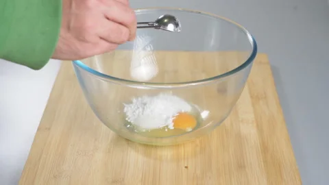 Adding sugar to raw eggs in a bowl before beating them. Preparing dough for Stock Footage 232411201