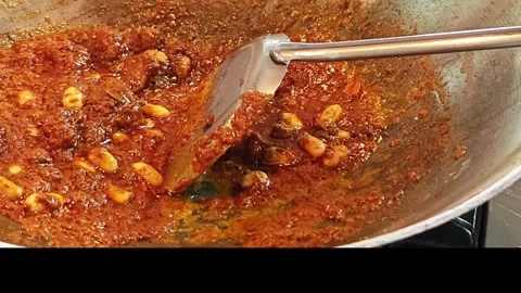 Adding sugar to Thai Massaman red curry paste in a wok. 動画素材 344560196
