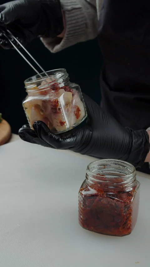 Adding sun-dried tomatoes to jar with smoked fish Stock Footage 308353266