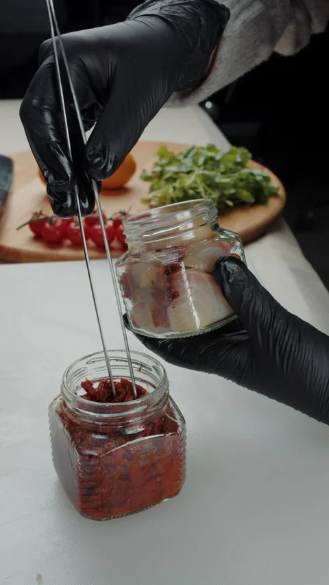 Adding sun-dried tomatoes to jar with smoked fish Stock Footage 308354188