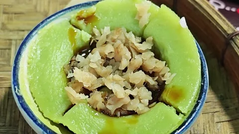 Adding sweet stir-fried turnip topping over green pandan steamed rice cake. Stock Footage 347241658