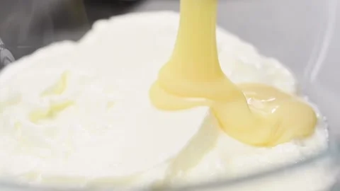 Adding sweetened condensed milk to the yogurt. Stock Footage 153459662