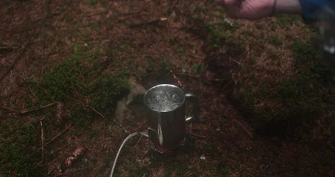 Adding tea leaves to a metal pot that is heated on a gas burner Stock Footage 244141186