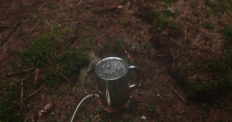 Adding tea leaves to a metal pot that is heated on a gas burner Stock Footage 244141190