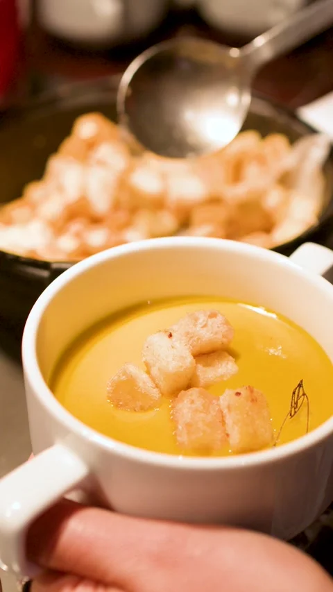 Adding Toasted Bread Croutons to a Creamy Pumpkin Soup Mug Video stock 334920702