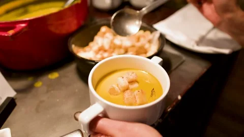 Adding Toasted Croutons to a White Mug of Creamy Pumpkin Soup Video stock 335797500
